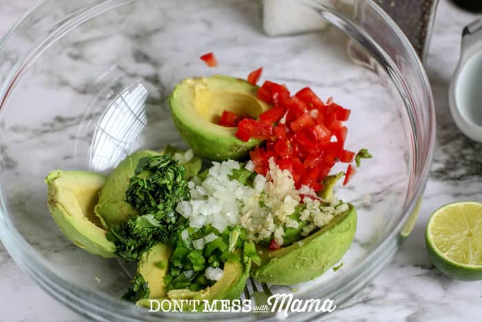 homemade guacamole ingredients in large glass bowl