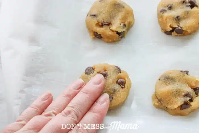 hand pressing down chocolate chip cookie