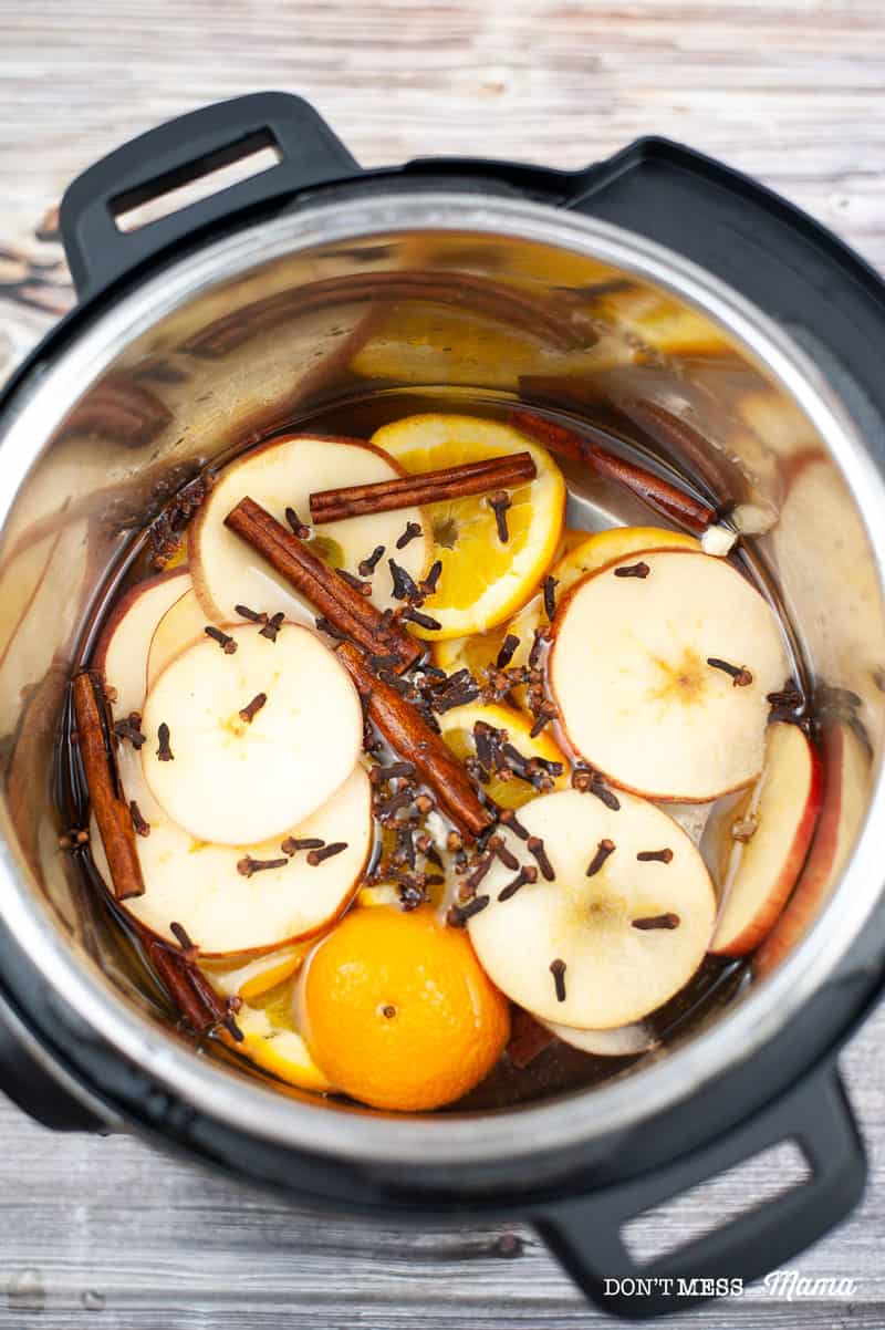 orange slices, apple slices, cloves, cinnamon sticks in an Instant Pot