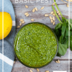 view from above of pesto in a glass bowl with lemon and basil