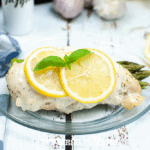chicken breast with lemon slices on glass plate