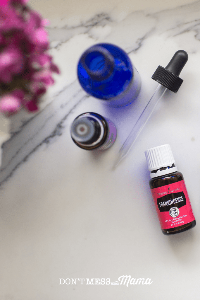 frankincense essential oil with blue dropper bottle and pink flowers