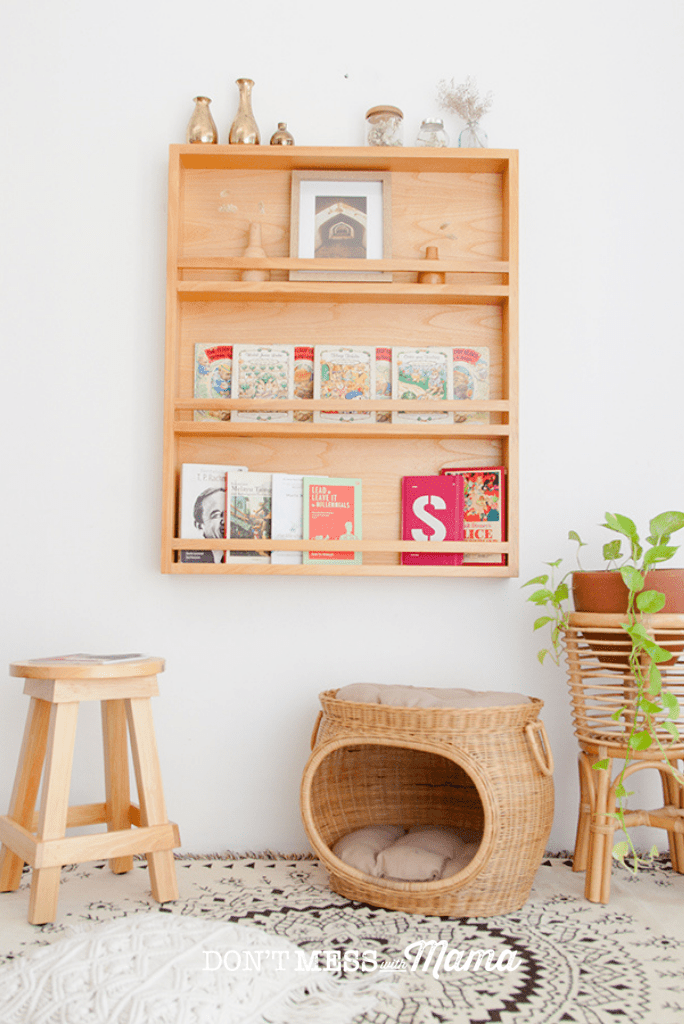 wooden book shelves on wall with stool and wicker basket on floor