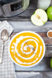 above view of orange butternut squash soup in a white bowl with spoon
