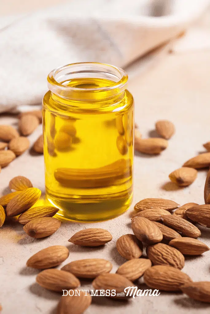 almond oil on a table with almonds nearby