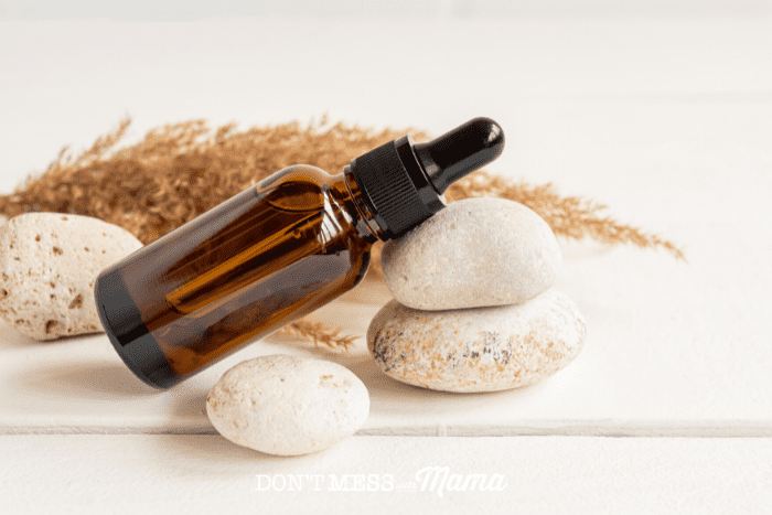 amber bottle of carrier oil balancing on pebbles