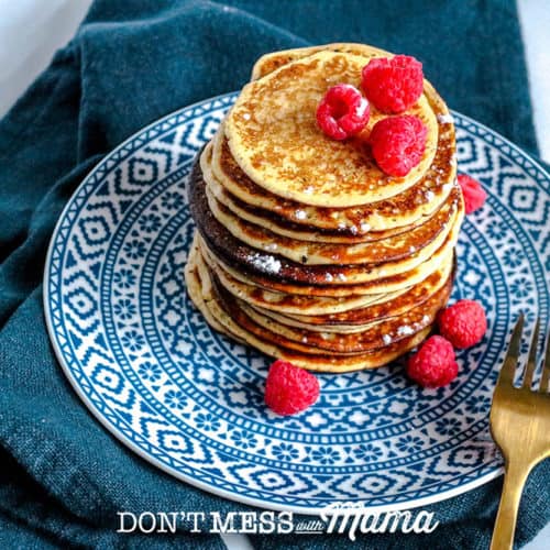 stack of low carb pancakes ona blue printed plate topped with raspberries