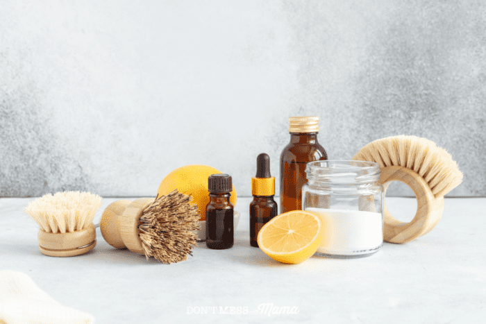 baking soda, scrubbing brushes, lemon, essential oils on a table top