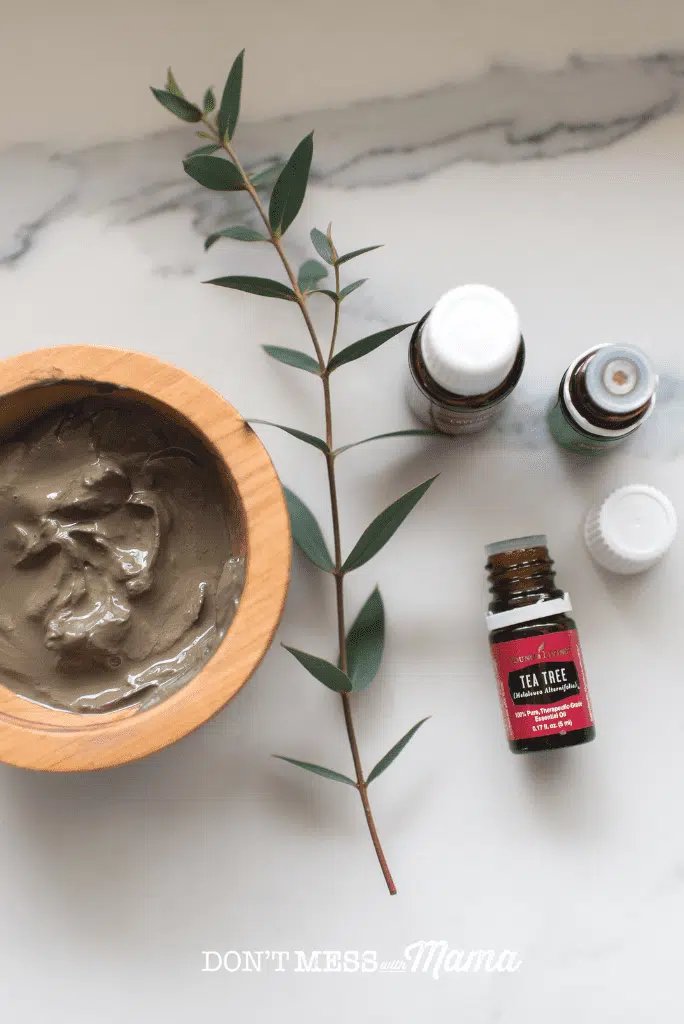 essential oils on marble surface with eucalyptus and mud mask in bowl 