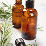 essential oil bottles on a white table with rosemary sprigs