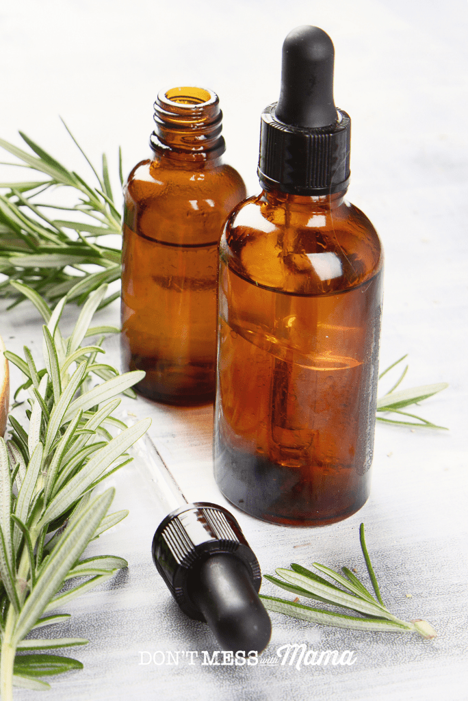 essential oil bottles next to a sprig of rosemary