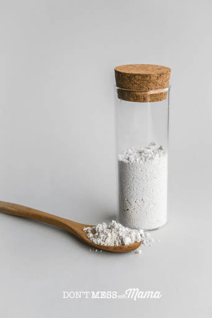 white powder in glass bottle with spoon of powder nearby
