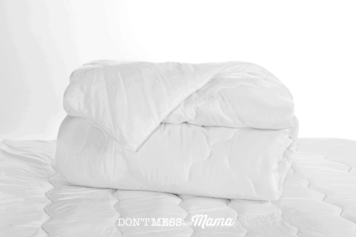 white blanket rolled up on mattress