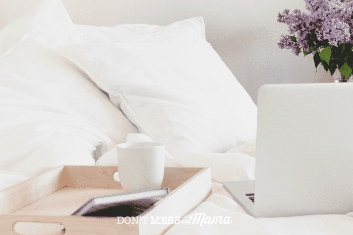white bedding with tray, laptop and mug