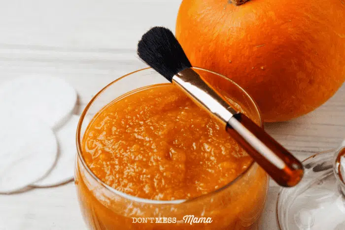 small jar of pumpkin face mask with face brush perched on top