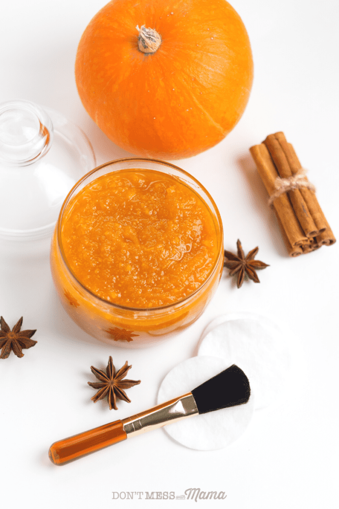 pumpkin and small jar of pumpkin face mask with cosmetic brush and cinnamon sticks