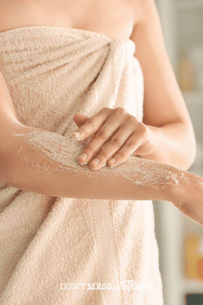 woman wrapped in towelusing body scrub on arm