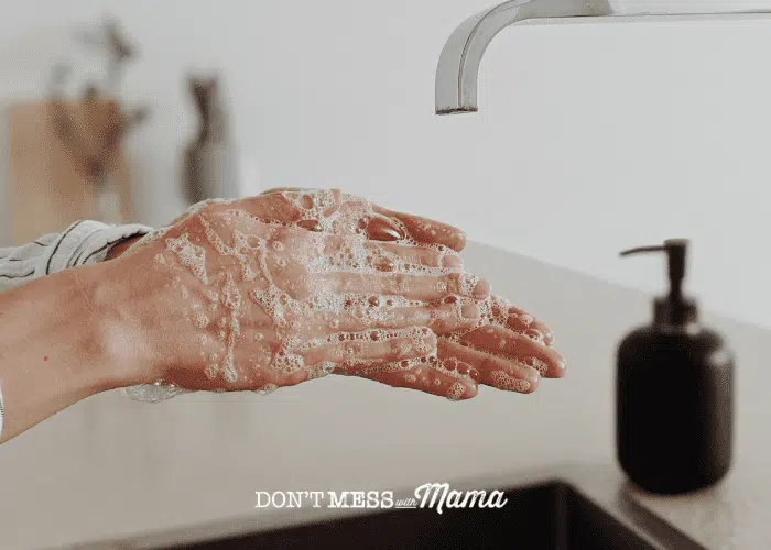 hands covered in bubbles with tap and handwash in background