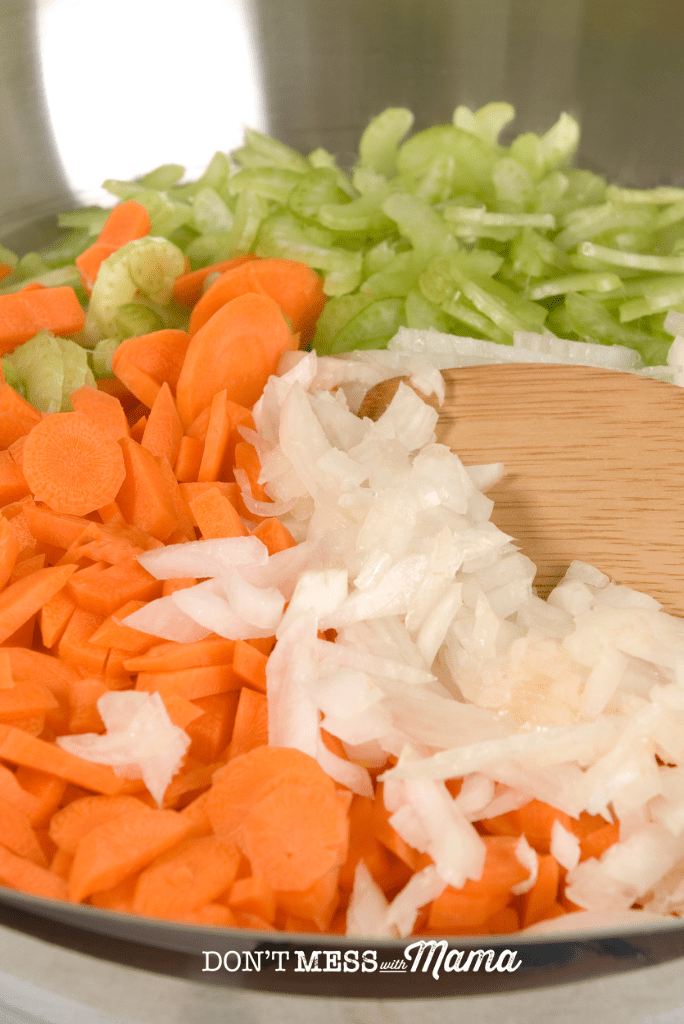 chopped carrot onion and celery in a bowl with wooden spoon
