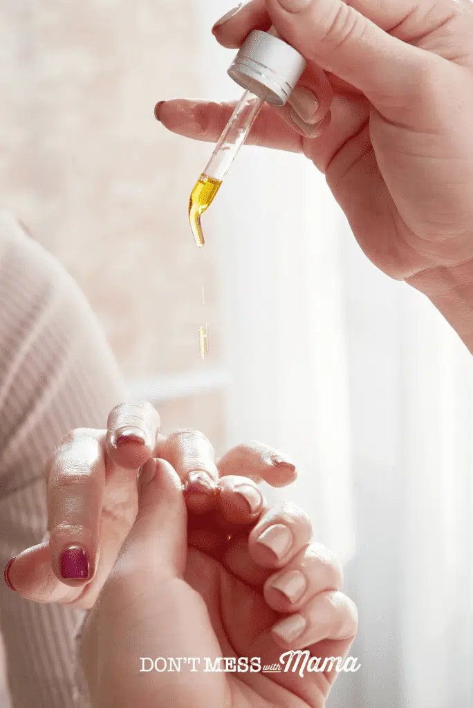 jojoba oil poured onto womans hand and nails