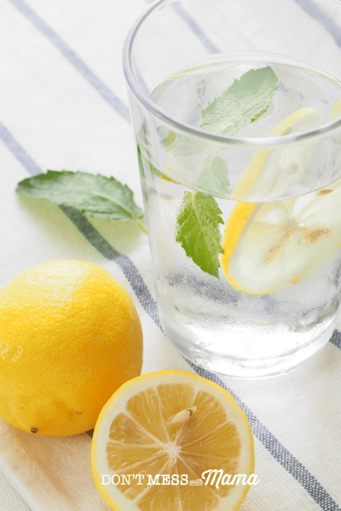 glass of lemon water with sliced lemon on table