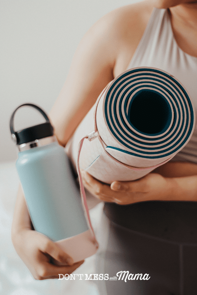 woman carrying pink yoga mat and blue water bottle