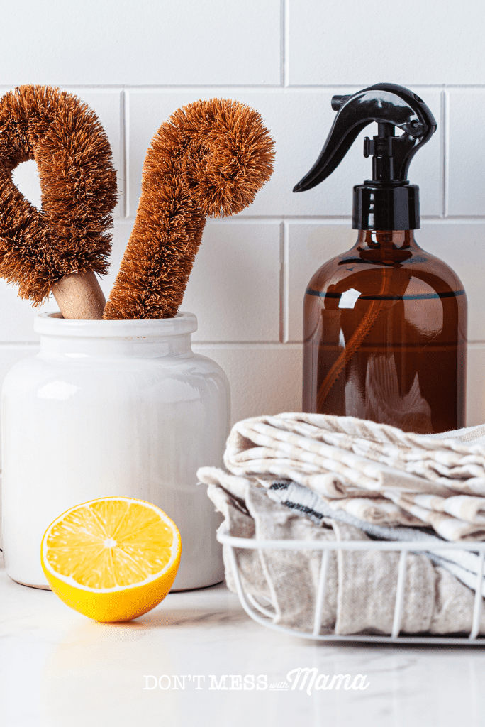 kitchen countertop with brushes spray bottle and lemon slice
