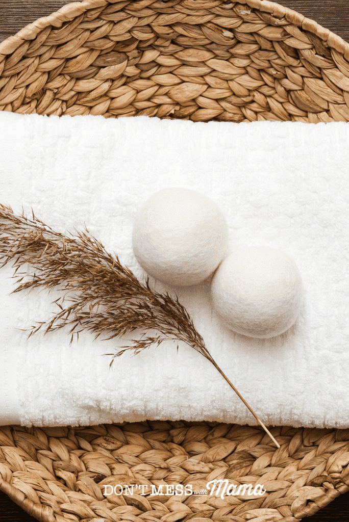 two wool dryer balls next to pampas grass on tray