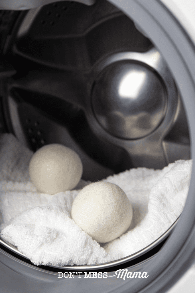 two wool dryer balls in dryer with white towel