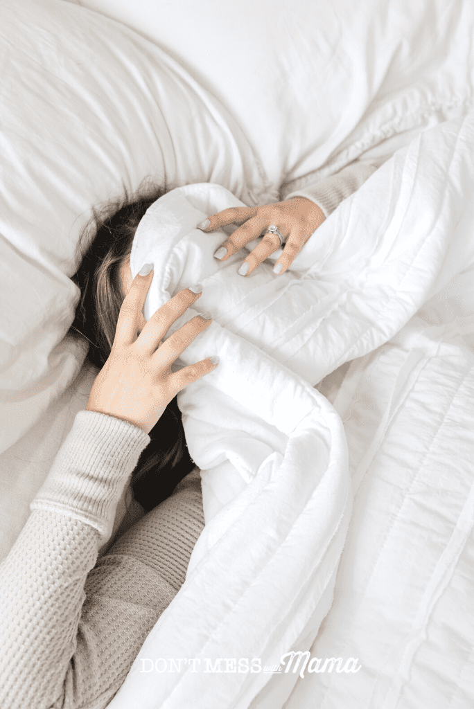 woman in bed with white quilt over eyes