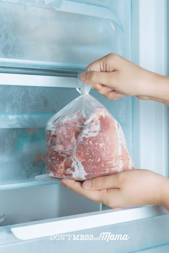 hands holding bag of frozen meat outside freezer
