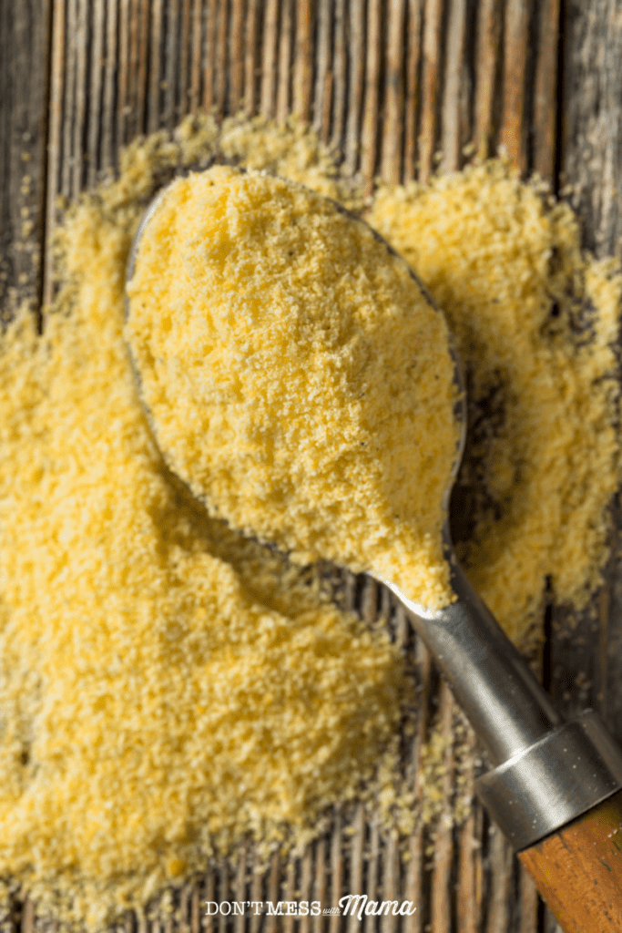ground corn meal on a spoon on a wooden table
