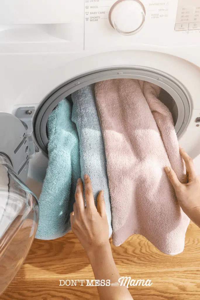 hands removing pink and blue towels from washing machine