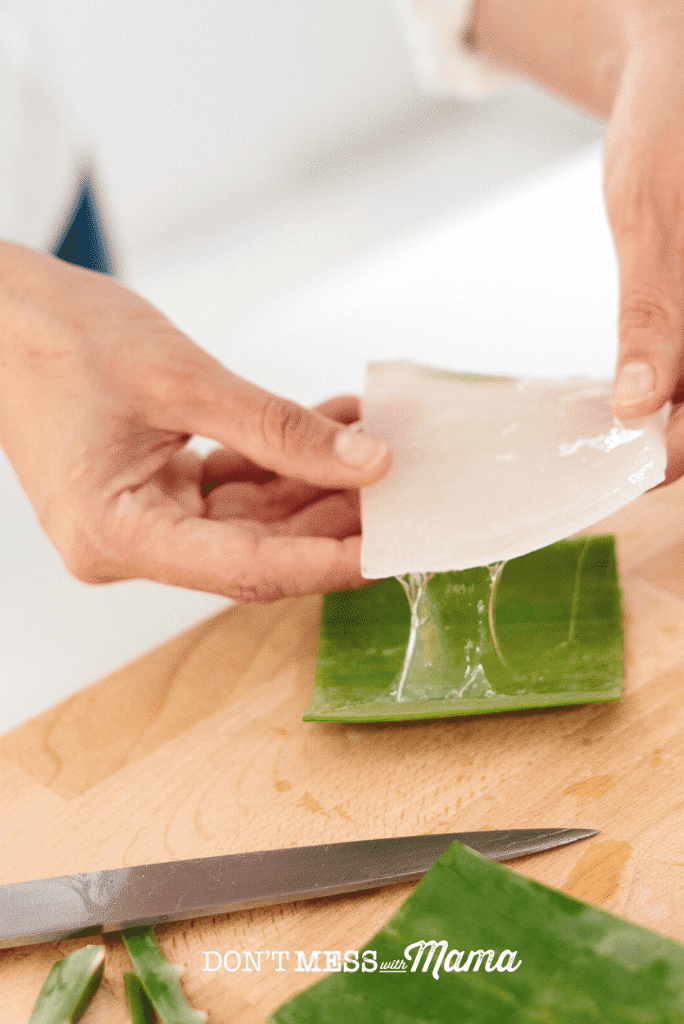 hand slicing aloe vera on chopping board