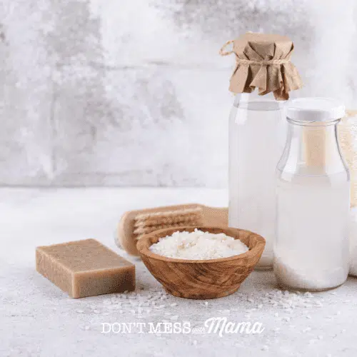 glass bottle of rice water with wooden bowl of rice on counter