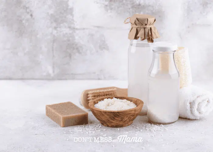 glass bottle of rice water with wooden bowl of rice on counter