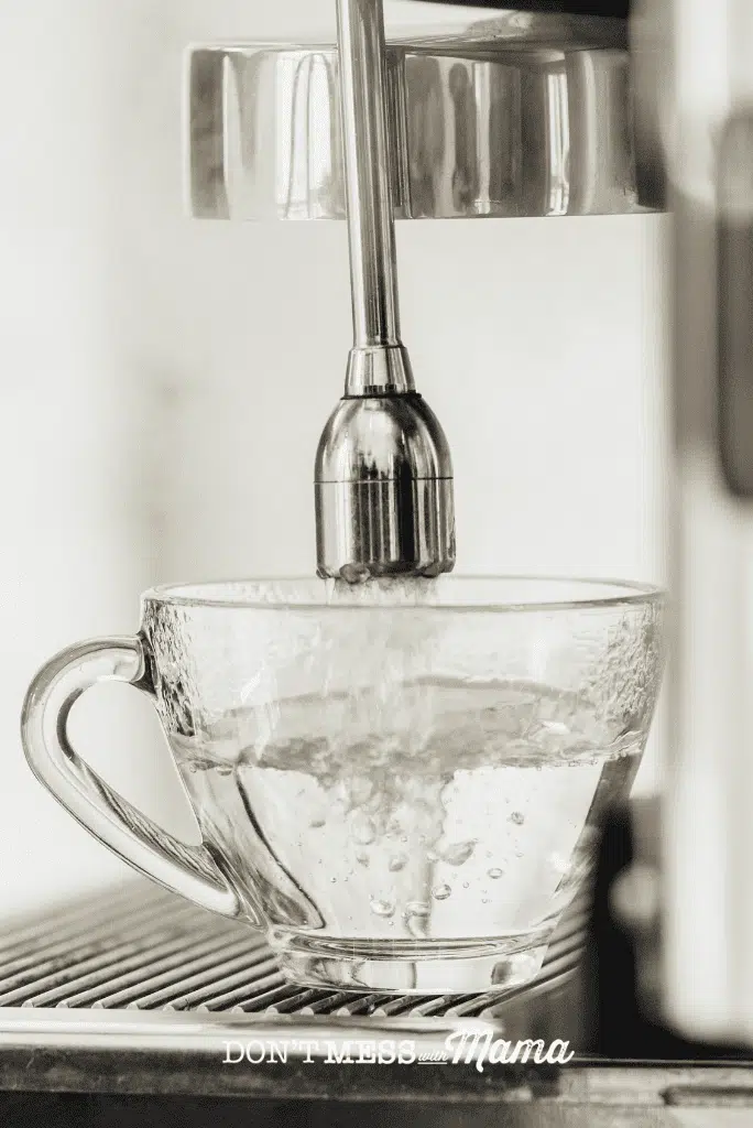 glass of boiling water with steamer from coffee machine