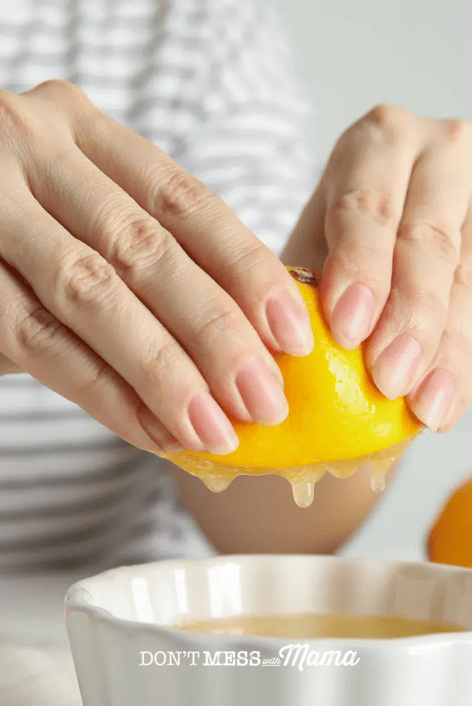 hand squeezing lemon into bowl