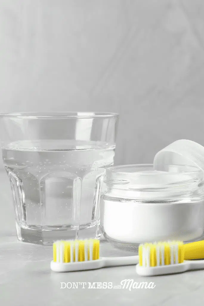 baking soda with glass of water and yellow toothbrushes