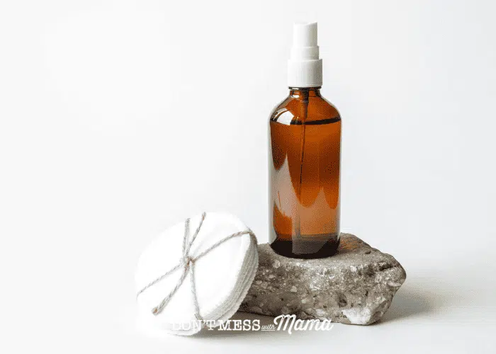 amber glass bottle with cotton rounds on a white background