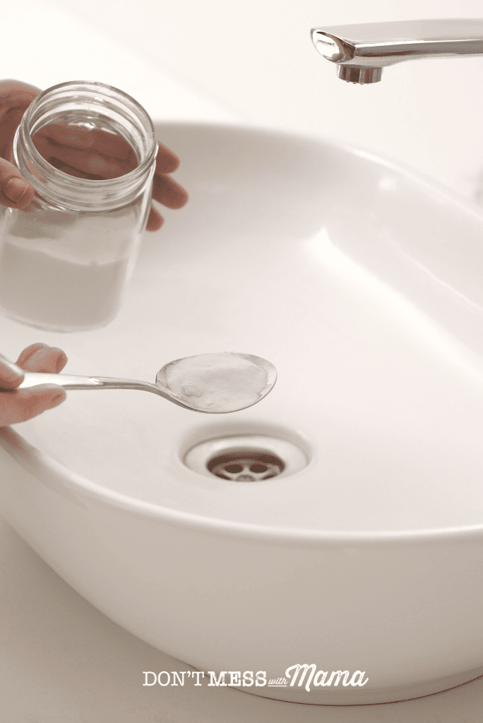 hand spooning baking soda into bathroom sink