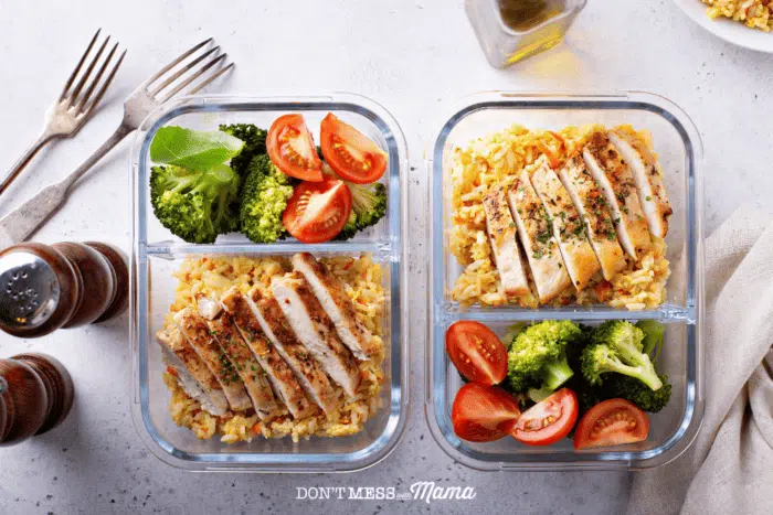 two glass food containers with rice, chicken and vegetables on a countertop