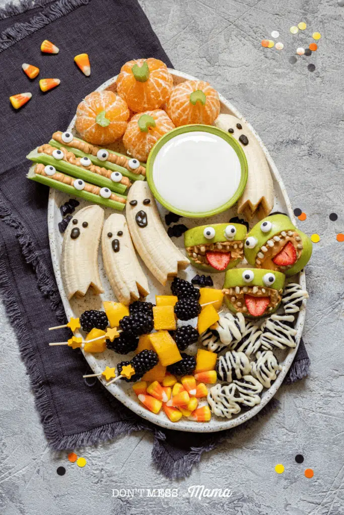 plate of healthy treats like bananas, oranges, apples in fun Halloween ghost and pumpkin shapes