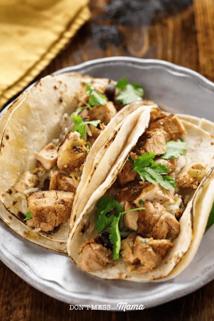 closeup of chicken tacos in corn tortillas on a plate